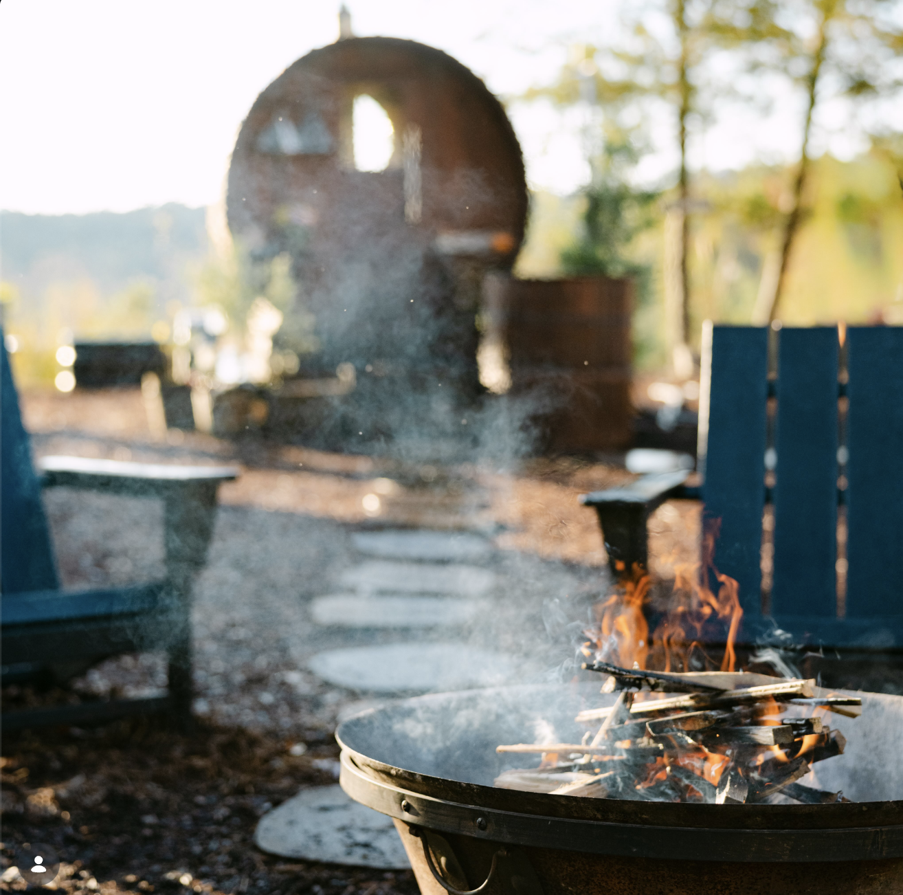 Fire pit burning in front of the wood-fired Drip sauna on the Greenspace at Seven Acres